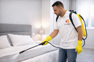 شركة مكافحة حشرات بدحضة – نجران عامل مختص يقوم برش الحشرات داخل غرفة النوم باستخدام معدات حديثة مع ظهور شعار الزهراء على الزي والصورة